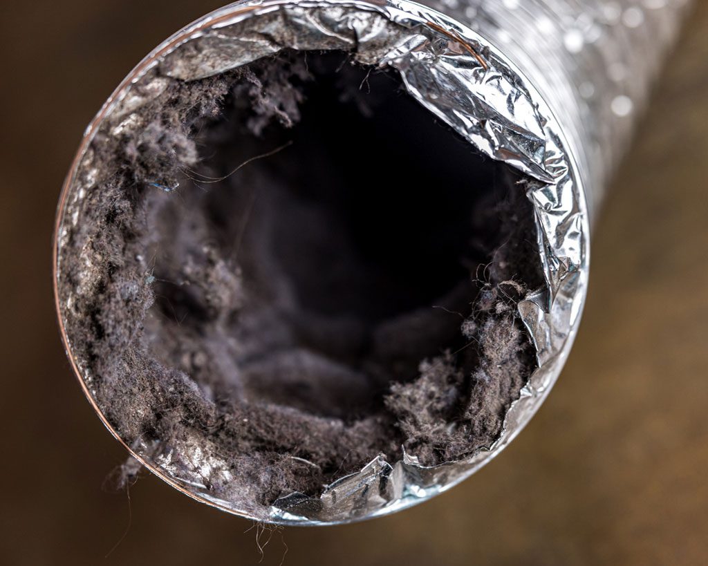 A dirty laundry flexible aluminum dryer vent duct ductwork filled with lint, dust and dirt